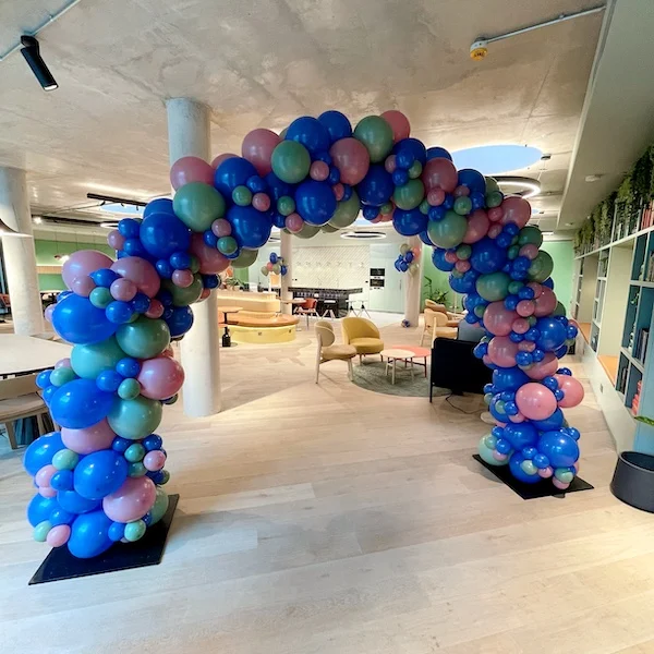 A bold organic balloon arch in blues, pinks and greens — the perfect way to welcome guests and elevate the whole space.