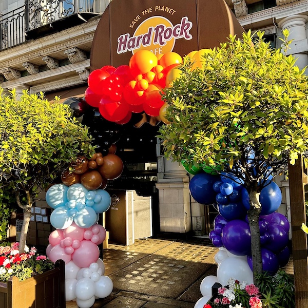 We created this vibrant rainbow balloon arch for Hard Rock Cafe London, transforming the entrance with a bold sweep of colour for their PRIDE celebrations. The design flows through the full spectrum — from rich reds and oranges to greens, blues, and purples — finishing with soft pastel tones and bright whites at the base. Framed by the café’s iconic exterior and surrounding greenery, the installation brought a warm, joyful welcome to guests while celebrating inclusivity and PRIDE in true Hard Rock style.